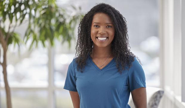 Nurse in blue scrubs smiling at camera