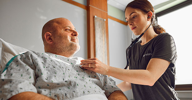 nurse using stethoscope to listen to patient heartbeat