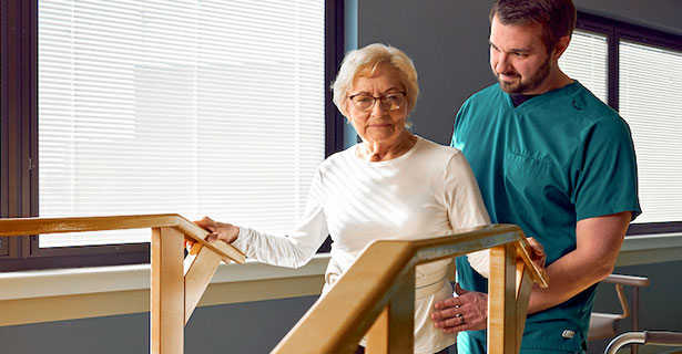 therapist helping elderly woman walk