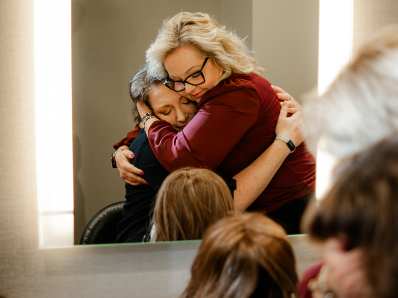 Two women hugging while getting a wig