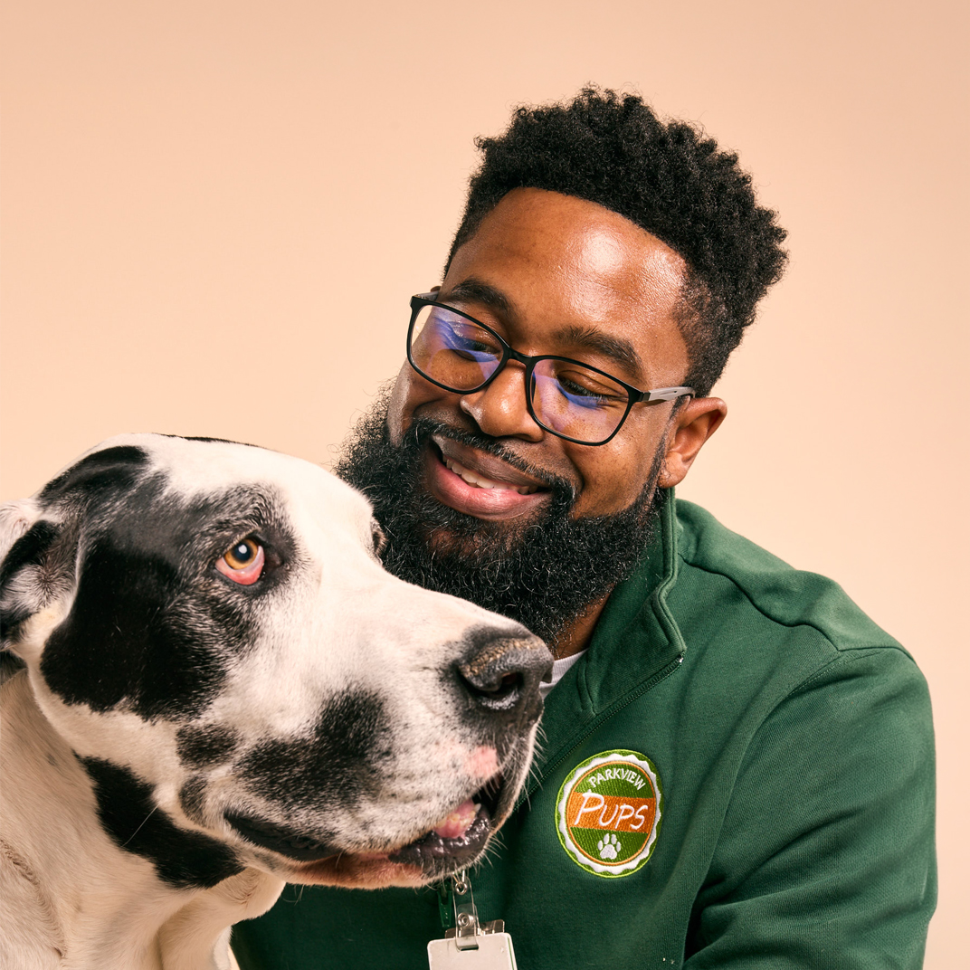 Black man smiling with a large dog
