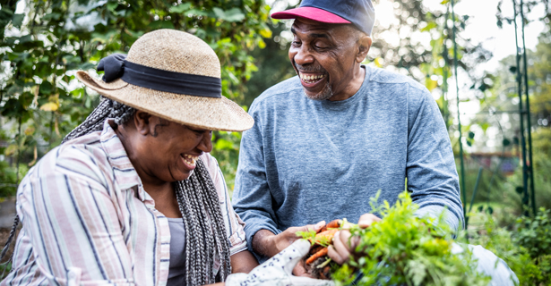 Older man and woman smiling while working in a garden
