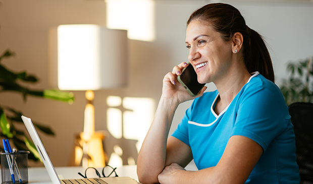 Woman wearing scrubs on phone