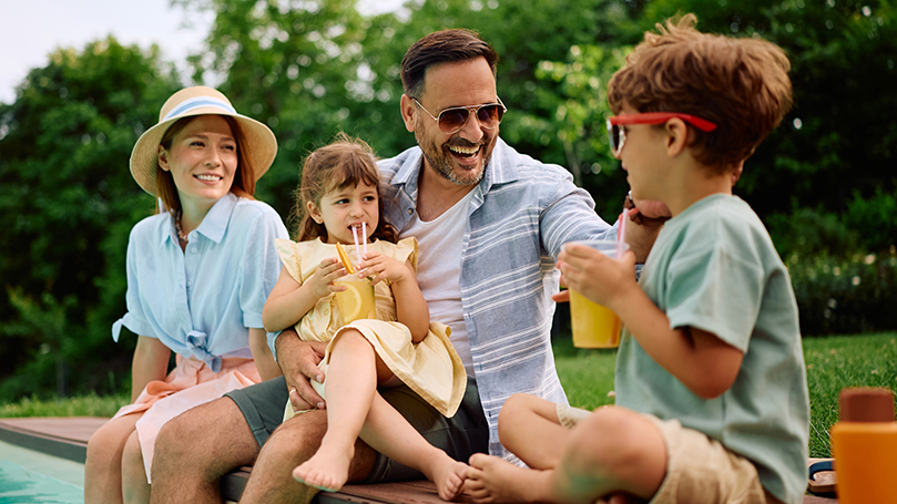 Family sitting on the edge of a pool in summer