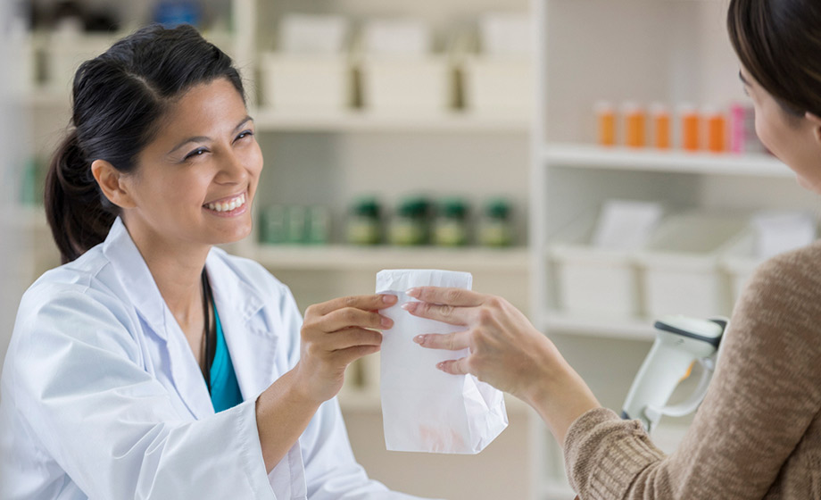 Pharmacist handing prescription to a customer