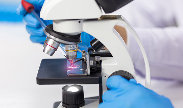 A technician stains a slide under a microscope