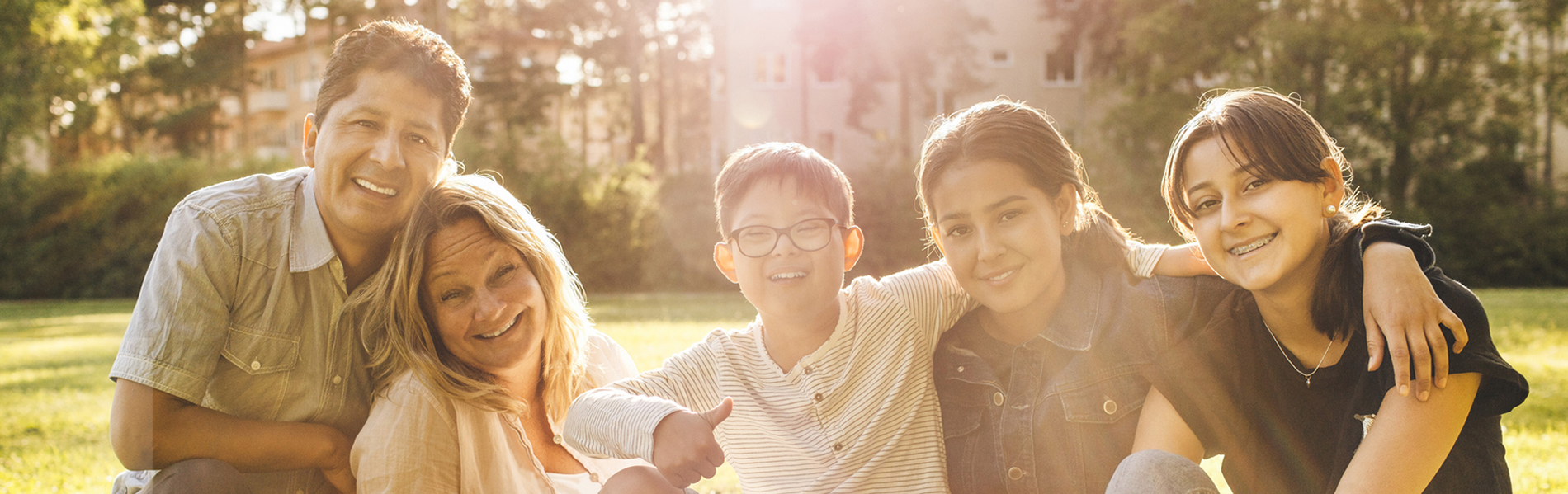 Family smiling at camera with sun flare